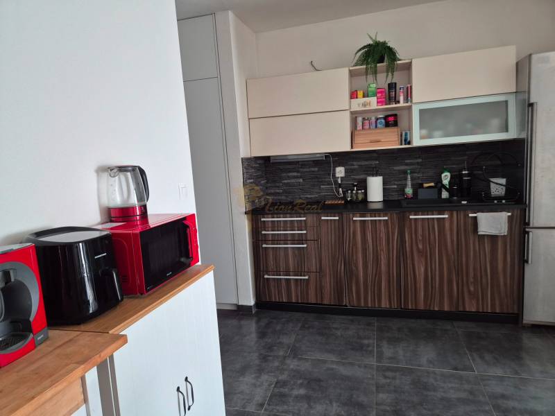 A kitchen in a 3-room apartment with modern appliances and decorative wood.
