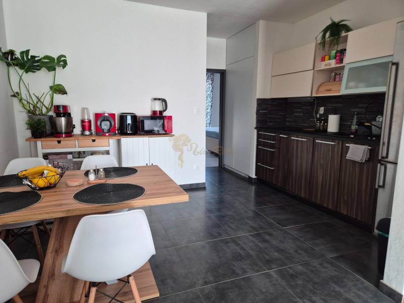 A kitchen in a 3-room apartment with a dark floor and wooden decor furniture.