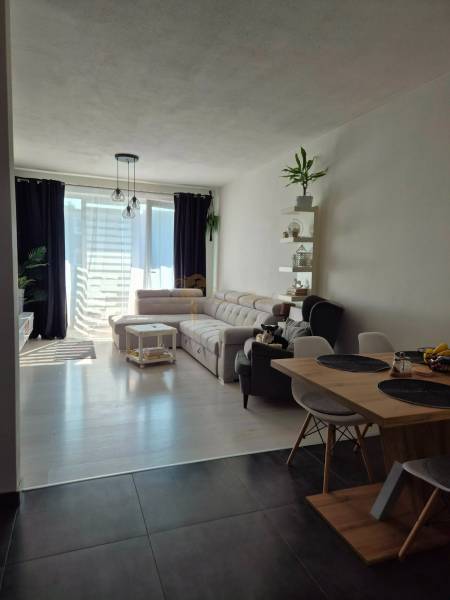 Interior of a 3-room apartment with a sofa, dining table, and wooden decor flooring.