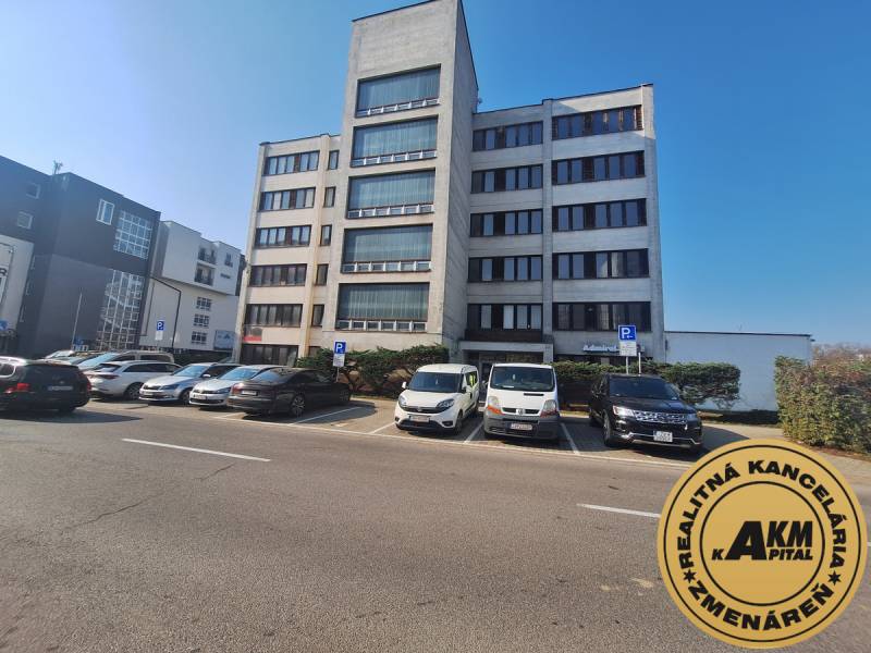 Office building on Tulská Street in the city of Zvolen, with a parking lot and parked cars.