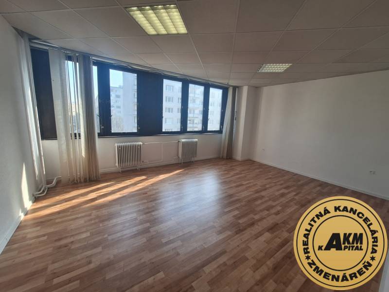 A spacious office with large windows and a wooden decor floor.