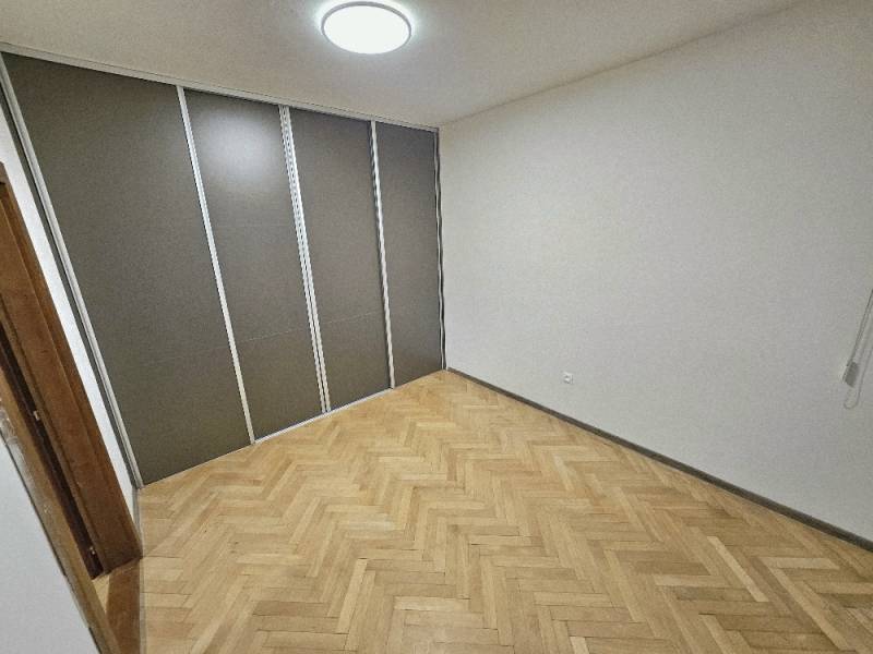 A room in a 2-room apartment with a wooden decor floor and storage space.