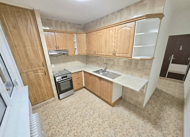 A kitchen with a kitchen unit in a new 2-room apartment, tiles and beige tiling.