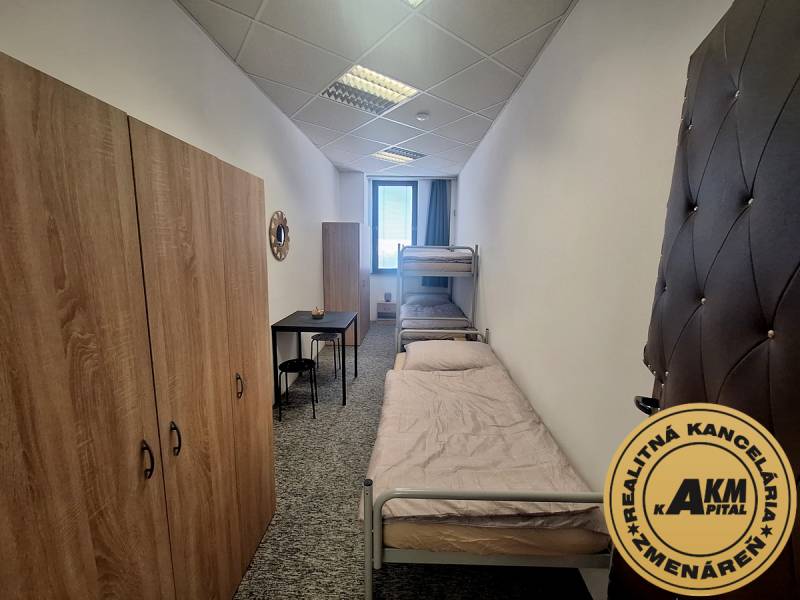 The interior of a building with two beds, wardrobes, and a small table in the room.