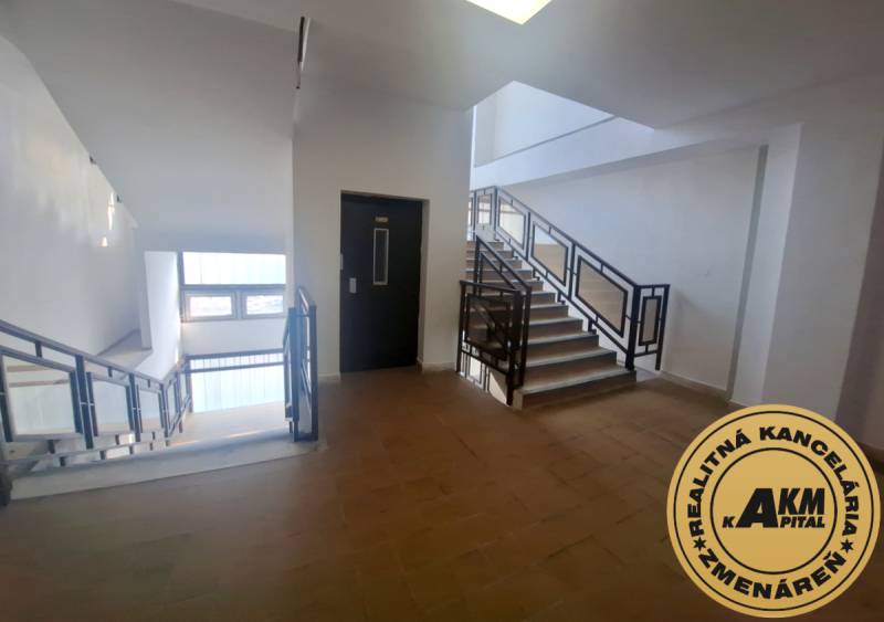 The interior of the building with a staircase and an elevator, floor with wooden decor.