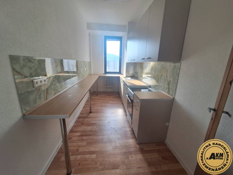 A kitchen in a building with a wooden decor floor and a green kitchen countertop.
