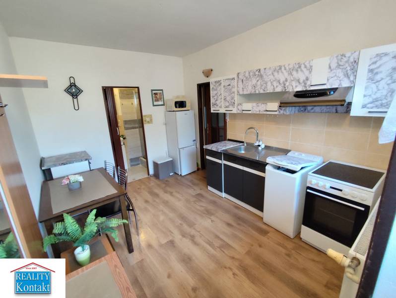 A kitchen in a studio apartment with a wood-patterned floor, nicely furnished and functional.