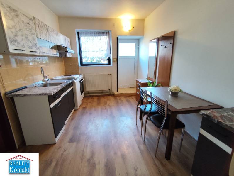 A kitchen in a studio apartment with a wood-patterned floor and a dining table.