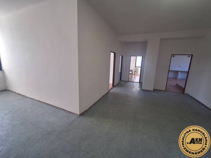 Interior photograph of a space with light-colored walls and three doors, flooring with a wooden decor.