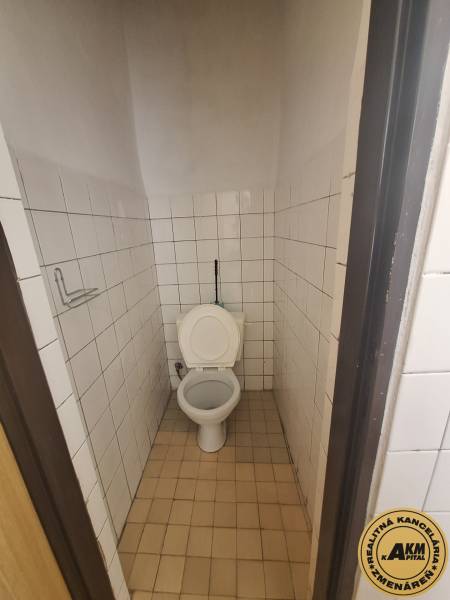 A restroom with white tiles in commercial premises.