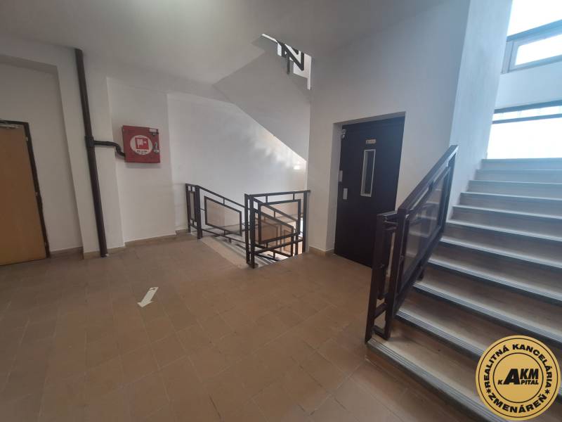 A corridor in commercial premises with a staircase and an elevator, tiled floor.