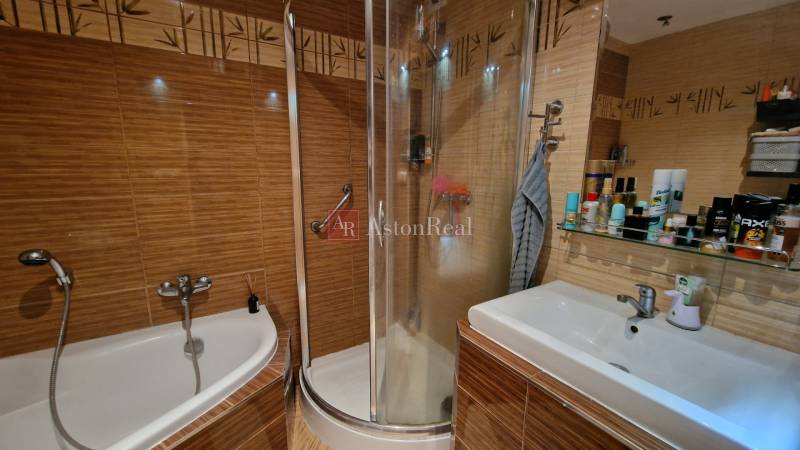 A bathroom in a 3-room apartment with a bathtub, shower, and sink.