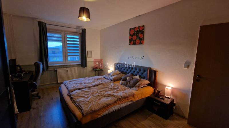A bedroom with a double bed, a desk, and a wooden decor floor in a 3-room apartment.
