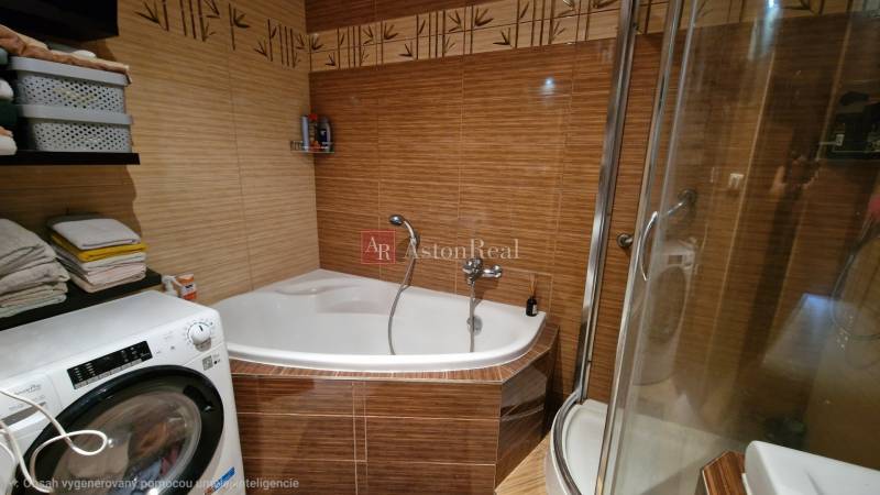 A bathroom in a 3-room apartment with a corner bathtub and a washing machine, tiles with a bamboo pattern.