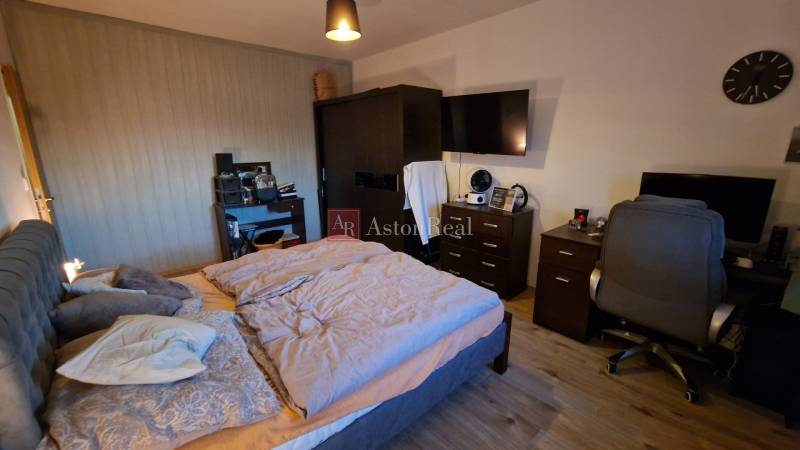 Bedroom in a 3-room apartment with a comfortable bed, a work desk, and a floor with a wooden decor.