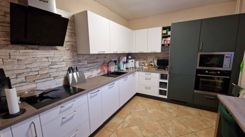 A kitchen in a 3-room apartment, light cabinets, stoneware tiles, kitchen appliances.