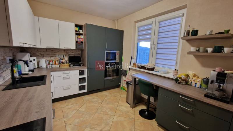 A kitchen in a 3-room apartment with a floor and kitchen cabinets with a wooden decor.