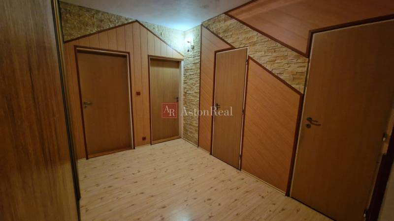A hallway with three doors and a floor with a wooden decor in a 3-room apartment.