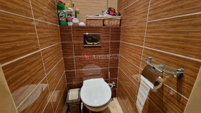 A toilet with brown tiles, a white bowl, and storage baskets in a 3-room apartment.