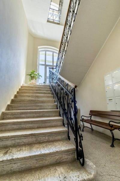 A staircase with a metal railing and a bench in the offices, illuminated by a large arched window.