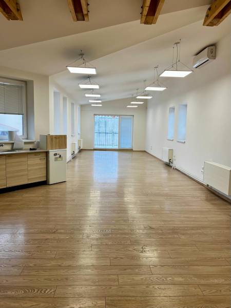 Offices with wood-patterned flooring and large windows, suitable for business.