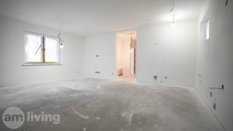 Interior of a family house under construction with a concrete floor, white walls, and electrical installation preparation.