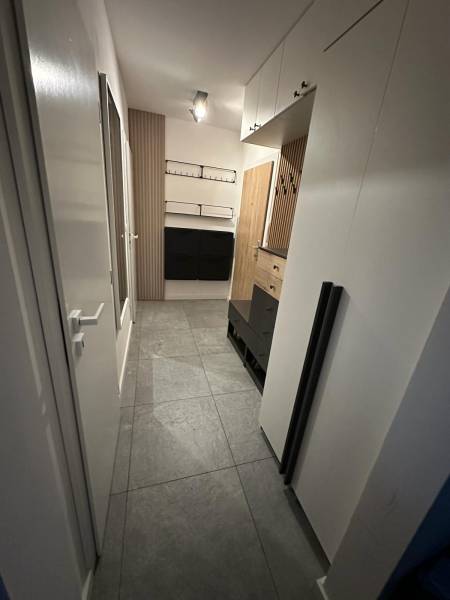 Hallway in a 2-room apartment with tiles, cabinets, and wooden wall panels.