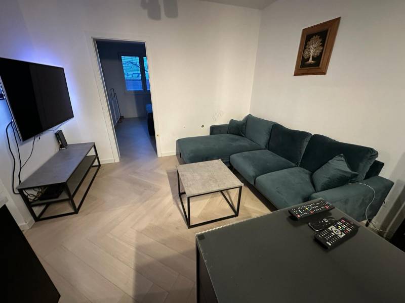Living room in a two-room apartment with a wooden decor floor and a comfortable sofa.