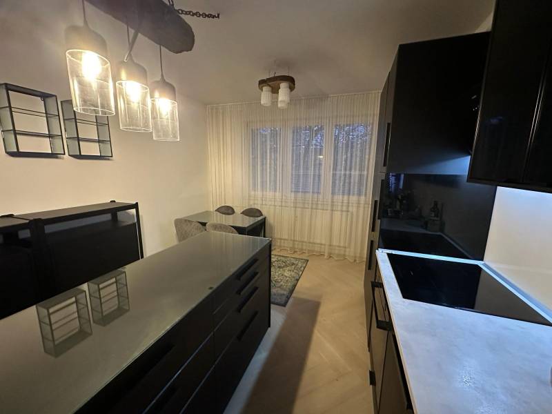A kitchen in a 2-room apartment with glass light fixtures and a wooden decor floor.