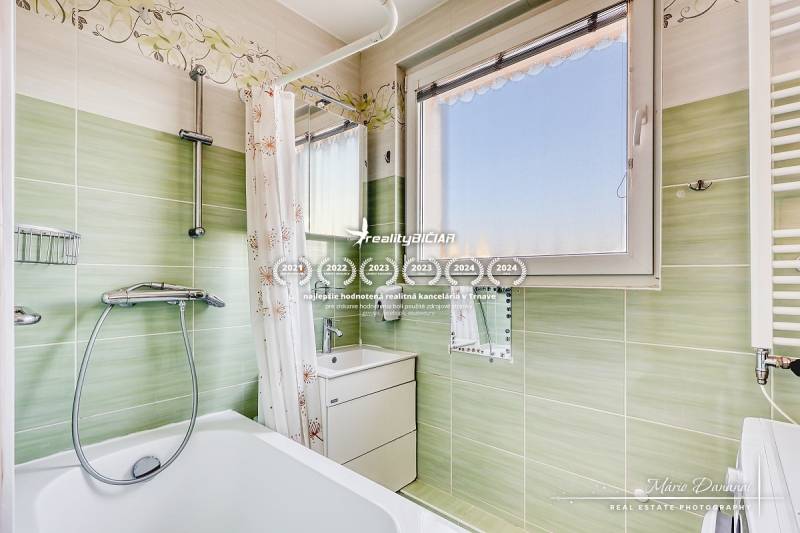 A bathroom in a 4-room apartment with a bathtub, green tiles, and a mirror.
