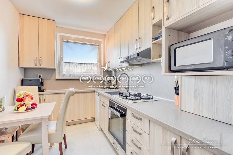 A kitchen in a 4-room apartment with fruit on the table and built-in appliances.