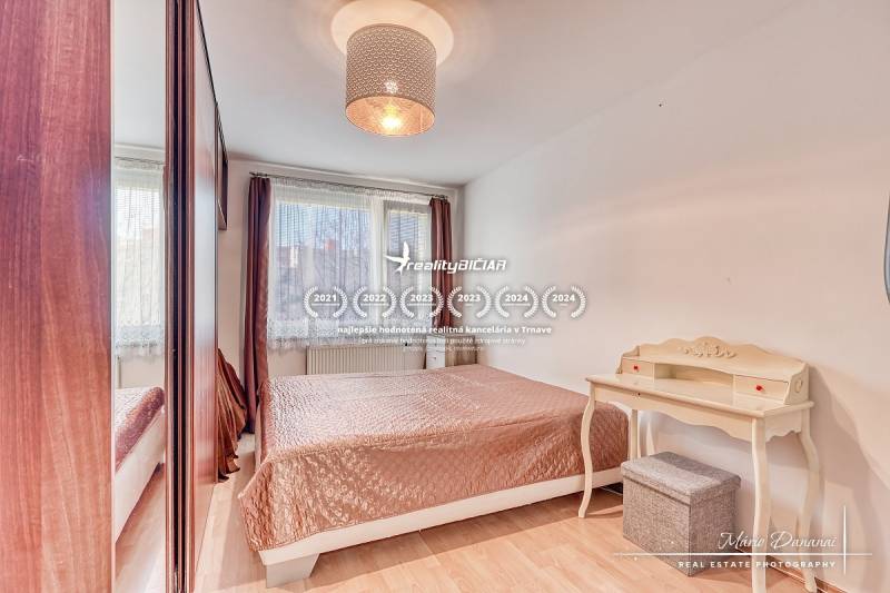 A bedroom in a 4-room apartment with a bed, a desk, and a wooden decor floor.