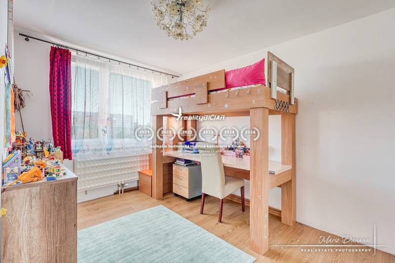 Children's room with a loft bed, wooden decor flooring, and toys on the shelves.