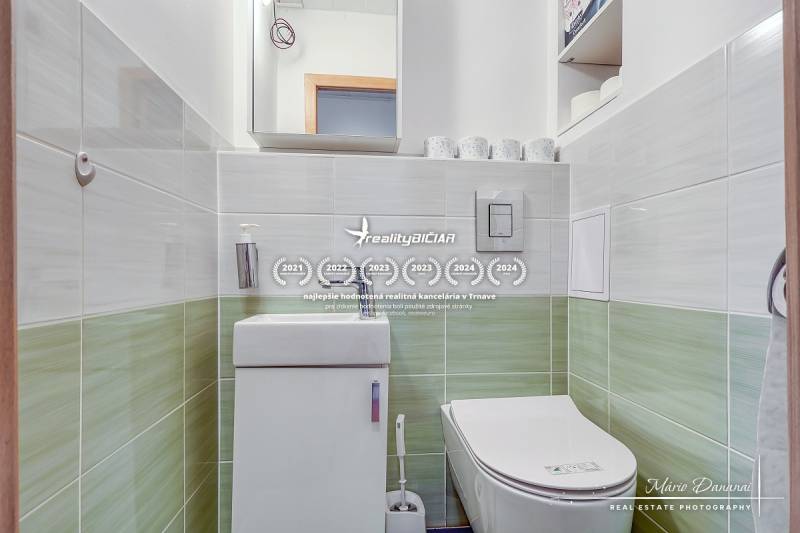 A bathroom in a 4-room apartment with a toilet and a sink, with tiled walls.