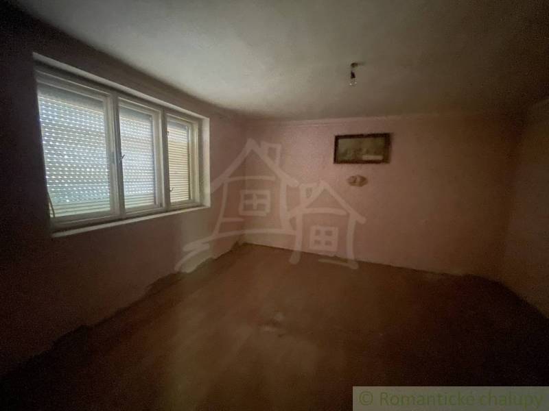 An empty room in a family house with wood-patterned flooring and a large window.
