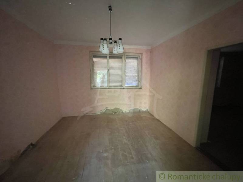 A room in a family house with pink walls and a wooden decor floor.