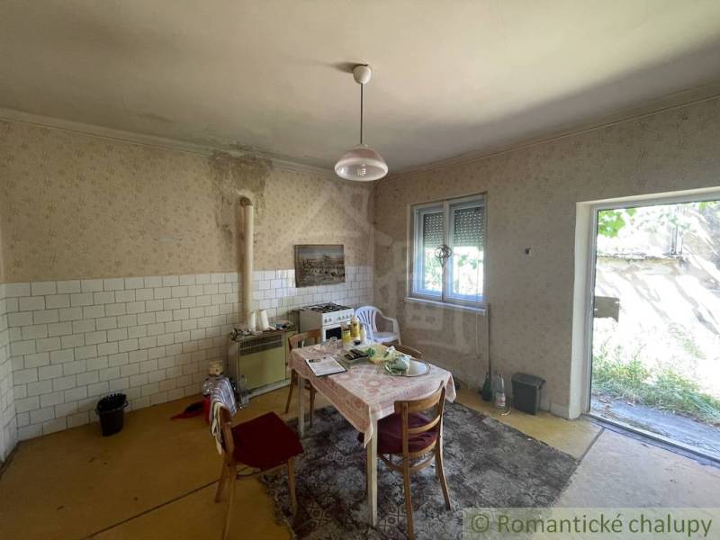A kitchen in a family house with a table, tiles, and access to the garden.