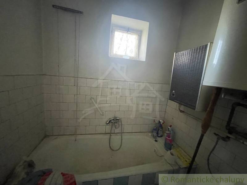A bathroom in a family house with tiles on the walls and an old bathtub.