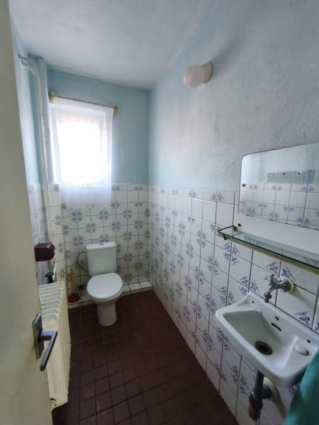 A bathroom in a family house with blue walls and tiles, a window with a curtain.