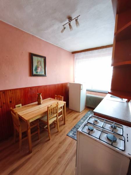 A kitchen in a family house with a wooden table, a gas stove, and a floor with a wooden decor.