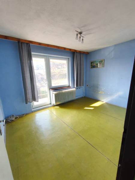 Blue walls, yellow floor, large window, radiator, curtains, lamp. Family house.