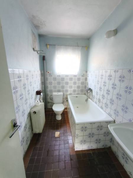 A bathroom in a family house with tiles and a bathtub, featuring characteristic patterned tiles.