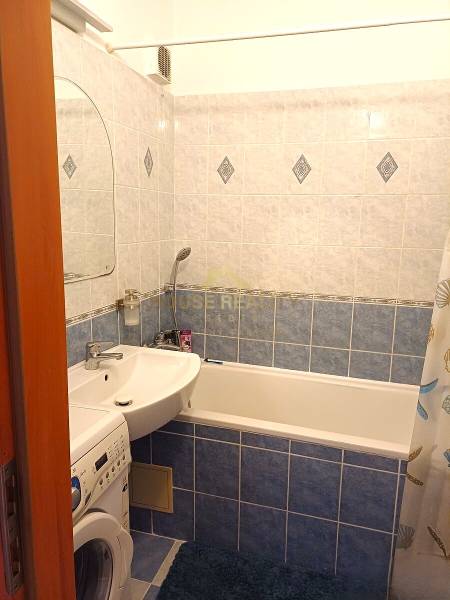 Bathroom in a 3-room apartment with a bathtub, sink, and washing machine. Blue tiles.