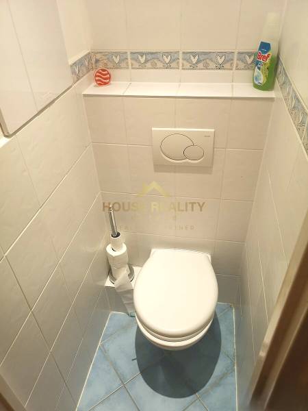A bathroom with white tiles and a blue floor in a 2-room apartment.