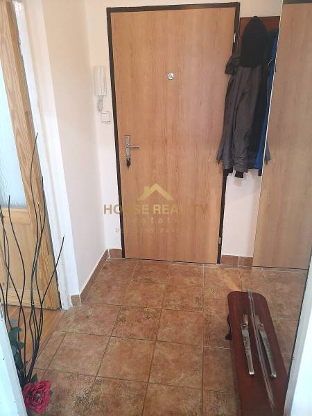 Entrance hall of a 2-room apartment with ceramic flooring and jackets on a coat rack.