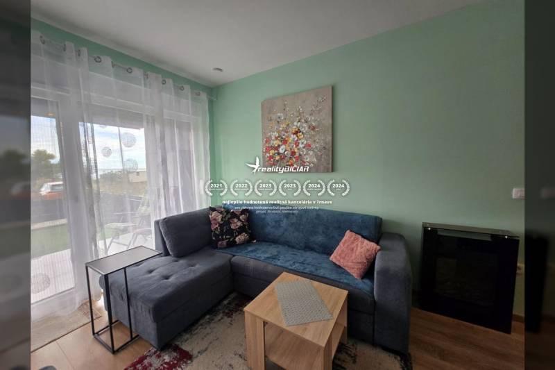 Living room of a holiday apartment with a sofa, table, decorations, and a window with a view.