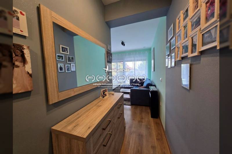 A hall in a holiday apartment with a wood-patterned floor and a mirror on the wall.