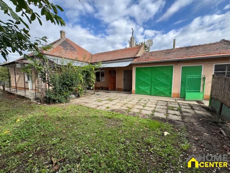 Garden and terrace at a family house in Komárno with garage doors and garden vegetation.