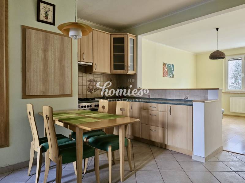Dining area with wooden furniture next to the kitchen in a 3-room apartment.