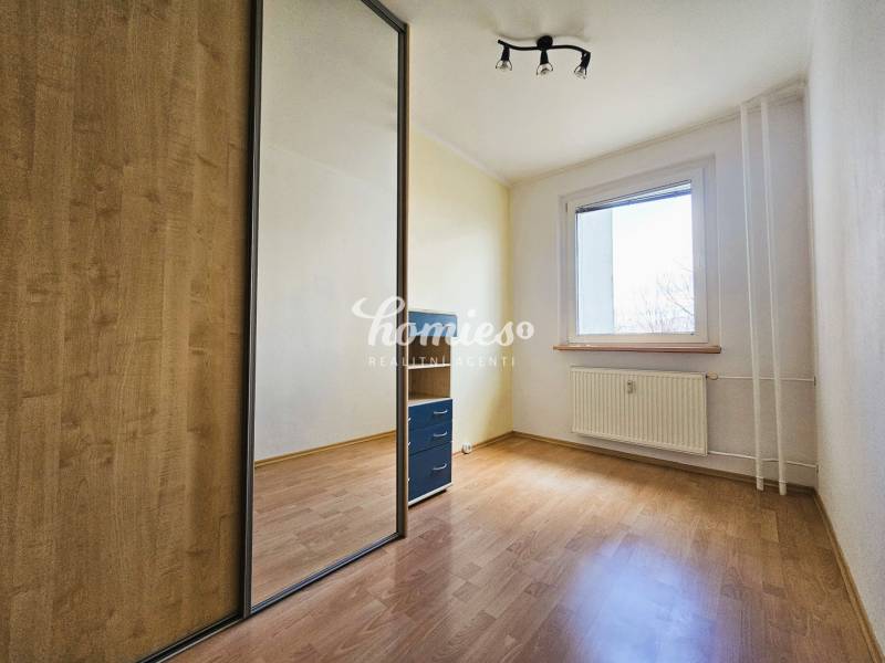 A room in a 3-room apartment with a wooden decor floor and a built-in wardrobe.